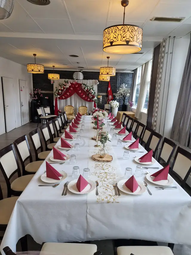 The full length of the hall laid for a party, red napkins and a flower runner down the centre of the table