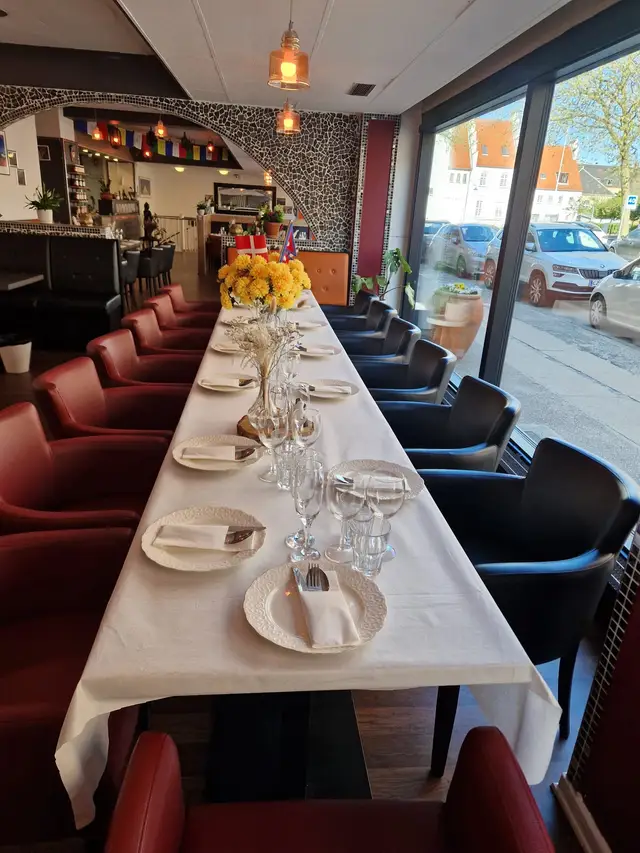 A table laid along the red banquette seating by the street window, set with wine glasses
