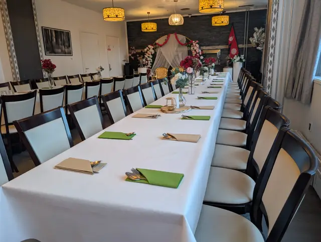 A table set with green napkins and kraft paper place cards, with a floral backdrop behind