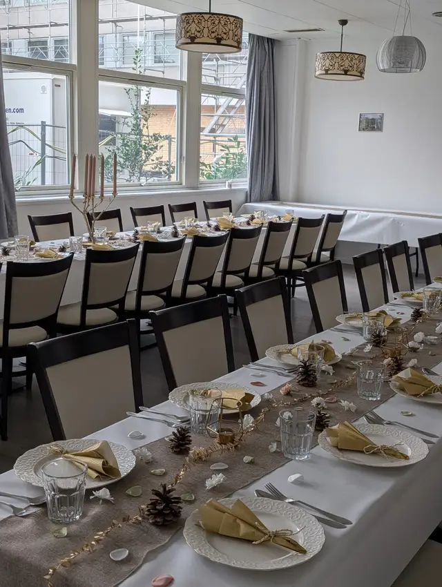 Daylight across a long table set with gold napkins, glassware and pine cone decorations
