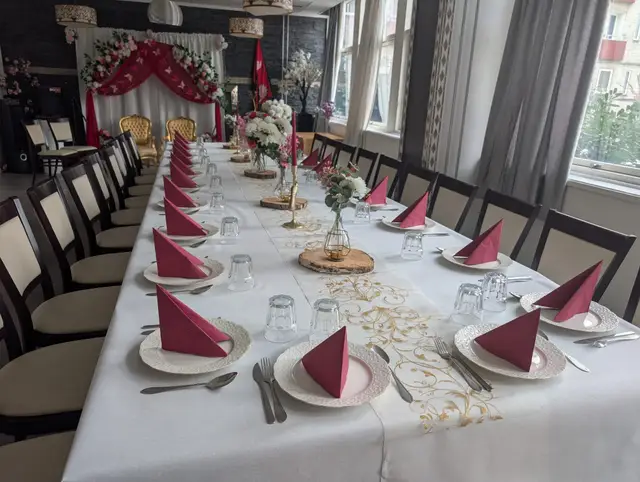 A close view of the place settings: red napkins, cutlery, glasses and petals on a wooden slice