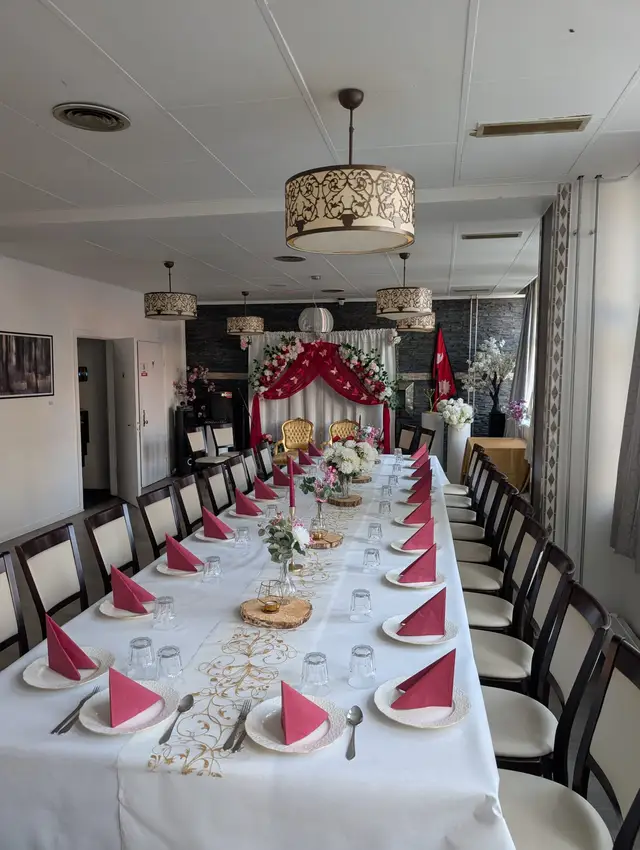 A long table with red napkins and wooden slice centrepieces against the dark feature wall