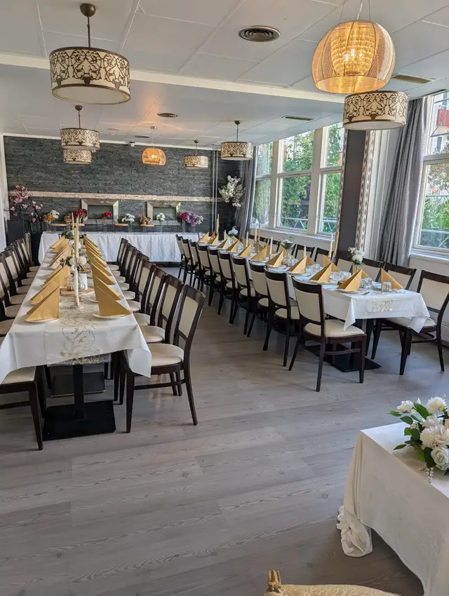 A long table with a gold runner and white chairs, daylight from the windows across the wooden floor