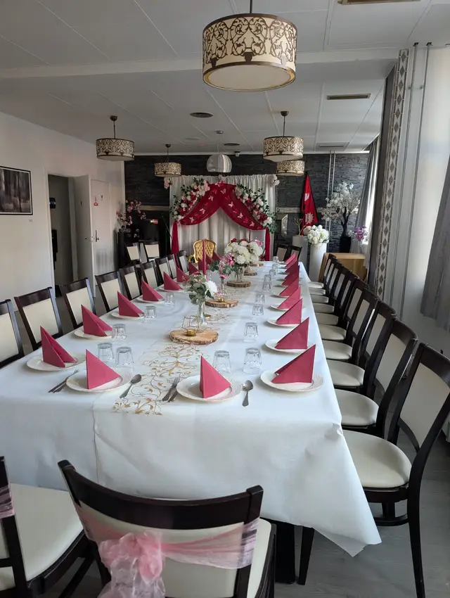 The hall laid out for a large party, red napkins along the table and a flower-dressed backdrop