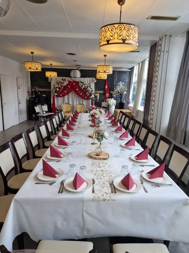 The hall seen down the length of the table, red and white drapes framing the far wall